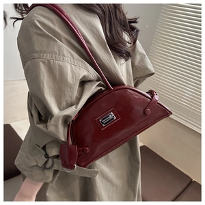 Close-up of a vintage wine red glossy patent leather underarm bag with metal plaque