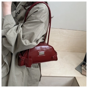 Macro detail of wine red glossy leather shoulder bag with metallic logo plaque