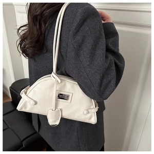 Side view of a creamy white crescent shoulder bag on a grey oversized blazer outfit