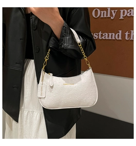 Detail of white ostrich embossed hobo bag with gold chain strap and fashion tag