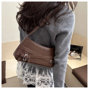 Brown matte underarm bag with cross-strap details and silver buckle on a model