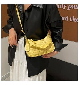 Detail of yellow ostrich texture underarm bag with metal chain and leather strap