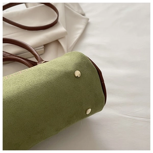 Close-up of green matte suede texture and gold metal protective feet on Boston bag