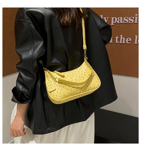Detail of yellow ostrich textured crescent bag featuring metal chain and zipper closure