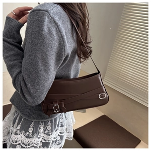 Detail of dark brown vintage faux leather shoulder bag with buckle and pleated side