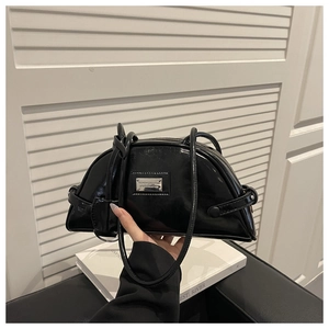 Detail of black faux leather half-moon shoulder bag with glossy finish and metal logo plate