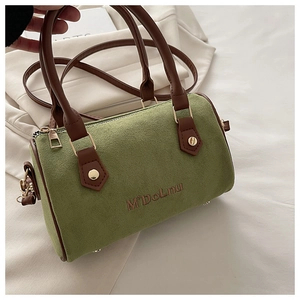 Close-up of green suede Boston bag featuring brown leather handles and gold metal zipper