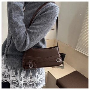 Detail of dark brown leather underarm bag with silver buckles and ribbon knot detail