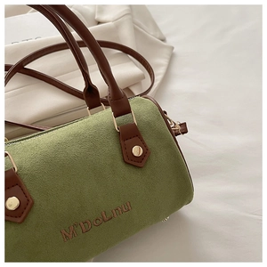 Close-up of green matte Boston bag with brown leather handles and gold metal rivets