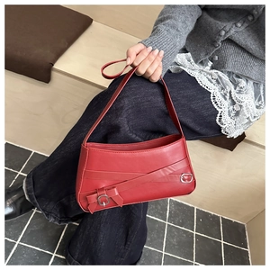 Close-up of red PU leather shoulder bag with decorative metal buckles and a bow