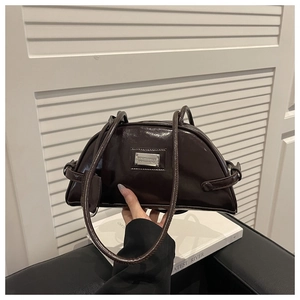 Close-up of a dark brown glossy baguette bag with silver metal plate and dual straps