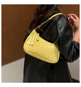Detail of yellow ostrich pattern handbag featuring elegant metal chain and leather strap