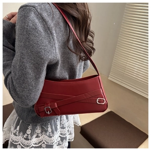Detail view of a dark red matte leather underarm bag with decorative metal buckles and straps