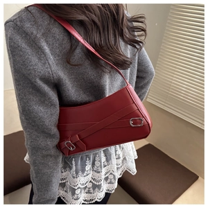 Close-up of vintage dark red leather shoulder bag with decorative straps and silver buckles