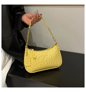 Close-up of yellow ostrich pattern hobo bag with gold chain strap and fashion tag