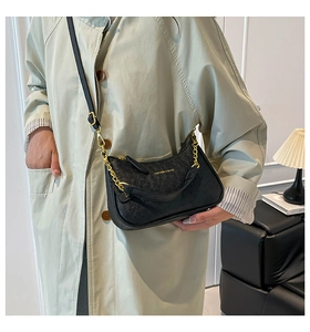 Detail of black ostrich embossed leather shoulder bag with gold chain and logo