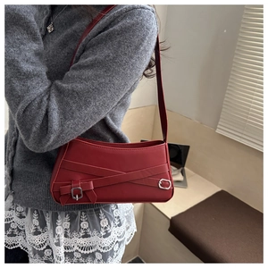 Detail of dark red shoulder bag with matte leather finish and silver buckle accents