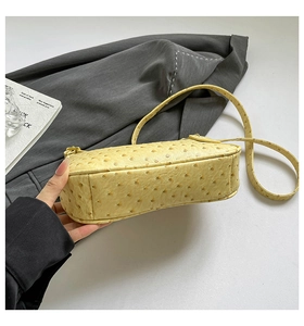 Detail view of cream crescent bag featuring unique ostrich leather texture and side stitching