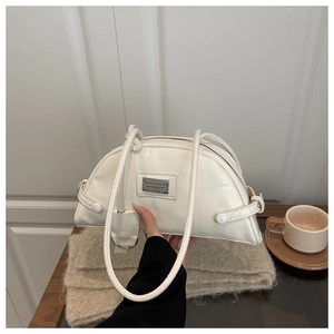 Detail of cream white crescent shoulder bag in glossy patent leather with silver plaque