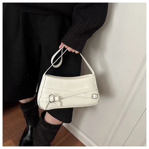 Detailed view of white shoulder bag with decorative bow and metal buckle on black outfit