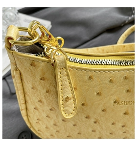 Macro shot of yellow ostrich-textured PU leather bag with gold hardware and fashion logo