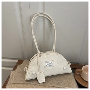 Close-up of cream shoulder bag with silver logo plaque and smooth leather texture