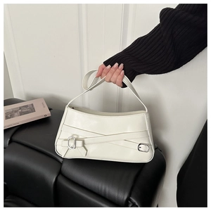 Detail of white glossy shoulder bag featuring layered straps and bow buckle decoration