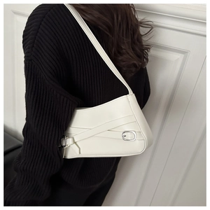Detail view of cream leather underarm bag with silver hardware on model's shoulder
