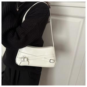 Close-up of white leather baguette bag with belt buckle detail on black sweater