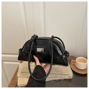 Detailed view of a black glossy hobo bag with silver plaque and slender shoulder straps