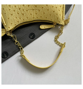 Macro shot of yellow ostrich texture moon bag with golden chain and fashion logo