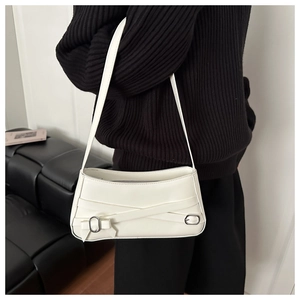 Detail of white leather underarm bag with cross straps and metal buckle shown on shoulder