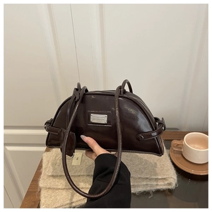 Detail of a dark brown glossy faux leather bowling bag with silver logo and slender handles