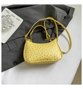 Macro shot of bright yellow ostrich texture crescent bag with gold chain and dual straps