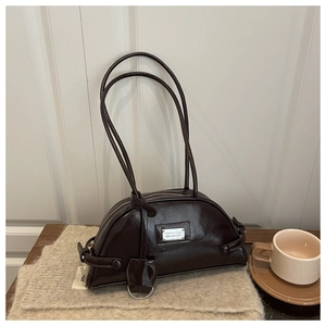Detail of dark brown semi-circular shoulder bag with glossy leather and metal plate
