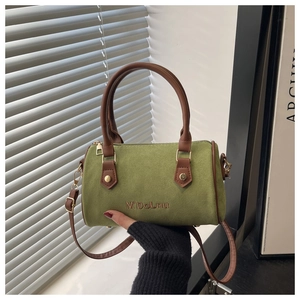 Detailed close-up of avocado green suede Boston bag with leather trim and gold hardware