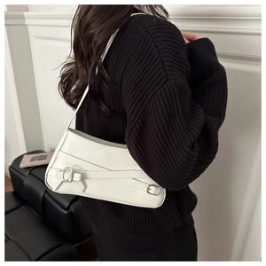 Detail of white leather underarm bag with decorative straps and silver metal buckles