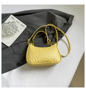 Detail of yellow crescent bag featuring ostrich embossed texture and gold chain strap