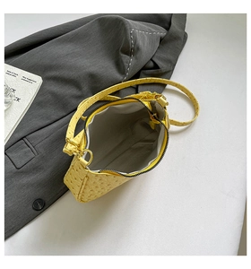 Detail view of yellow ostrich texture handbag with grey lining and zipper closure