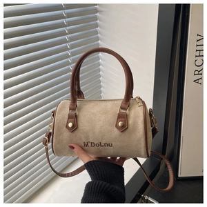 Close-up of beige suede Boston bag featuring brown leather handles and gold metal hardware