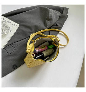 Detailed top view of a yellow ostrich leather shoulder bag with gold hardware and daily items