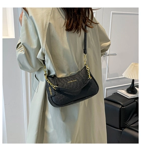 Detail of black ostrich embossed leather handbag with chunky gold chain decoration
