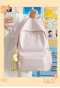 Detailed view of light pink nylon backpack featuring white bow embroidery and plush charm