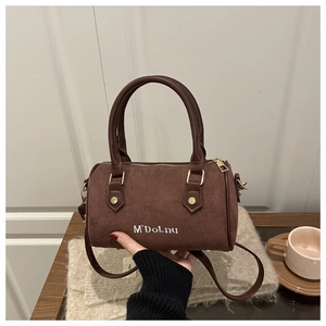 Brown frosted Boston bag with embroidered text and adjustable strap in lifestyle setting