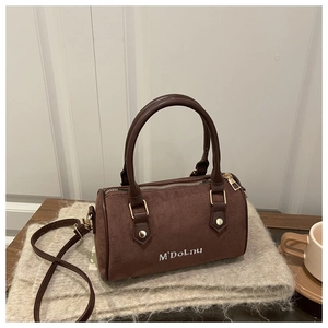 Detail of a brown suede Boston bag with gold hardware and logo on a cozy background
