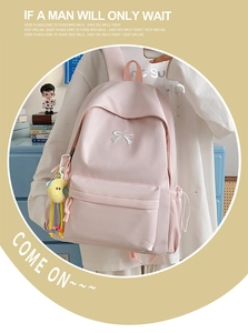 Close-up of pink nylon backpack featuring white bow embroidery and a moon plush pendant