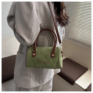 Detail of green Boston bag with brown handles and brand embroidery on grey suit