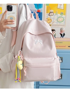 Detailed embroidery of a white bow on a soft pink nylon backpack with a cute yellow charm