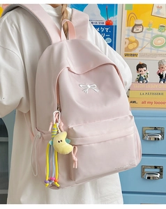 Pink nylon backpack detail showing embroidery and yellow moon plush accessory