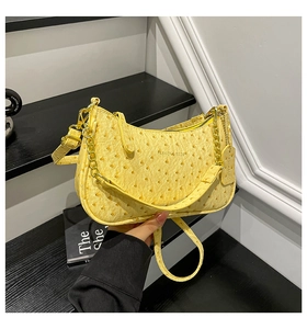 Detail of yellow ostrich-textured crescent bag with gold chain and metal zipper